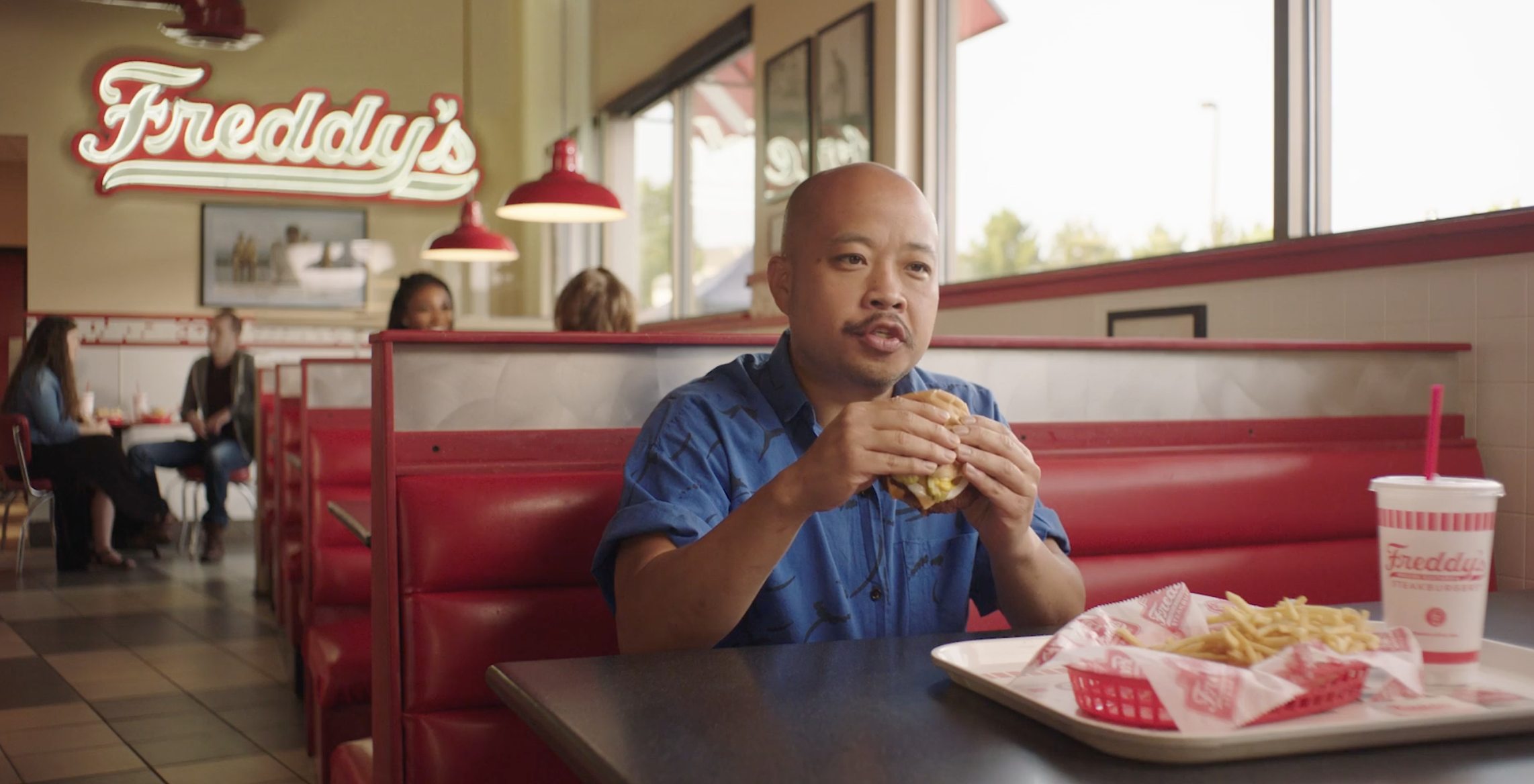 Man eating a burger in a Freddy's restaurant