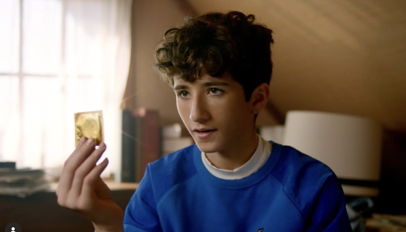 Young man holding a gold condom in Last Condom on Earth