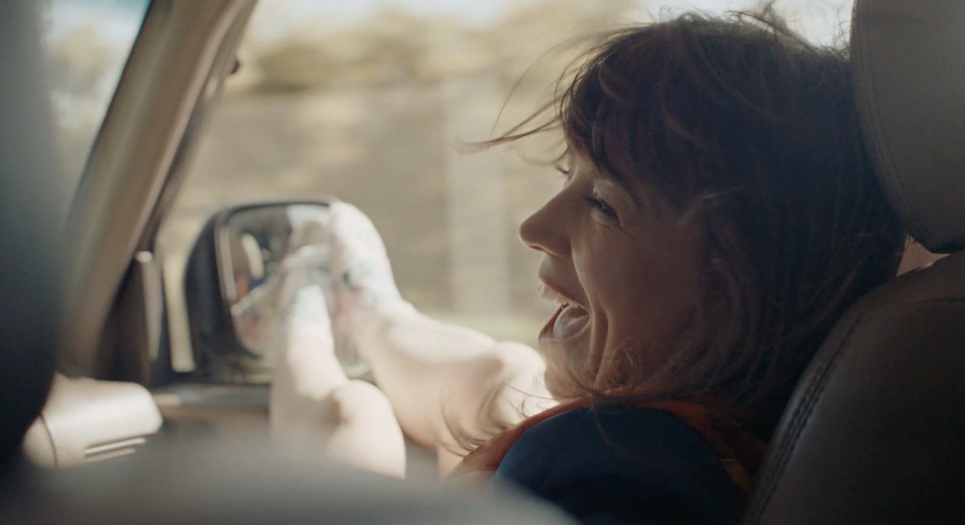 Woman smiling from the passenger seat of a car