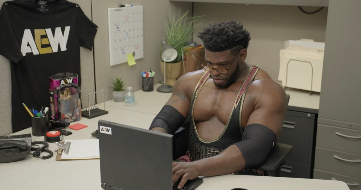 AEW wrestler working at a laptop in an office